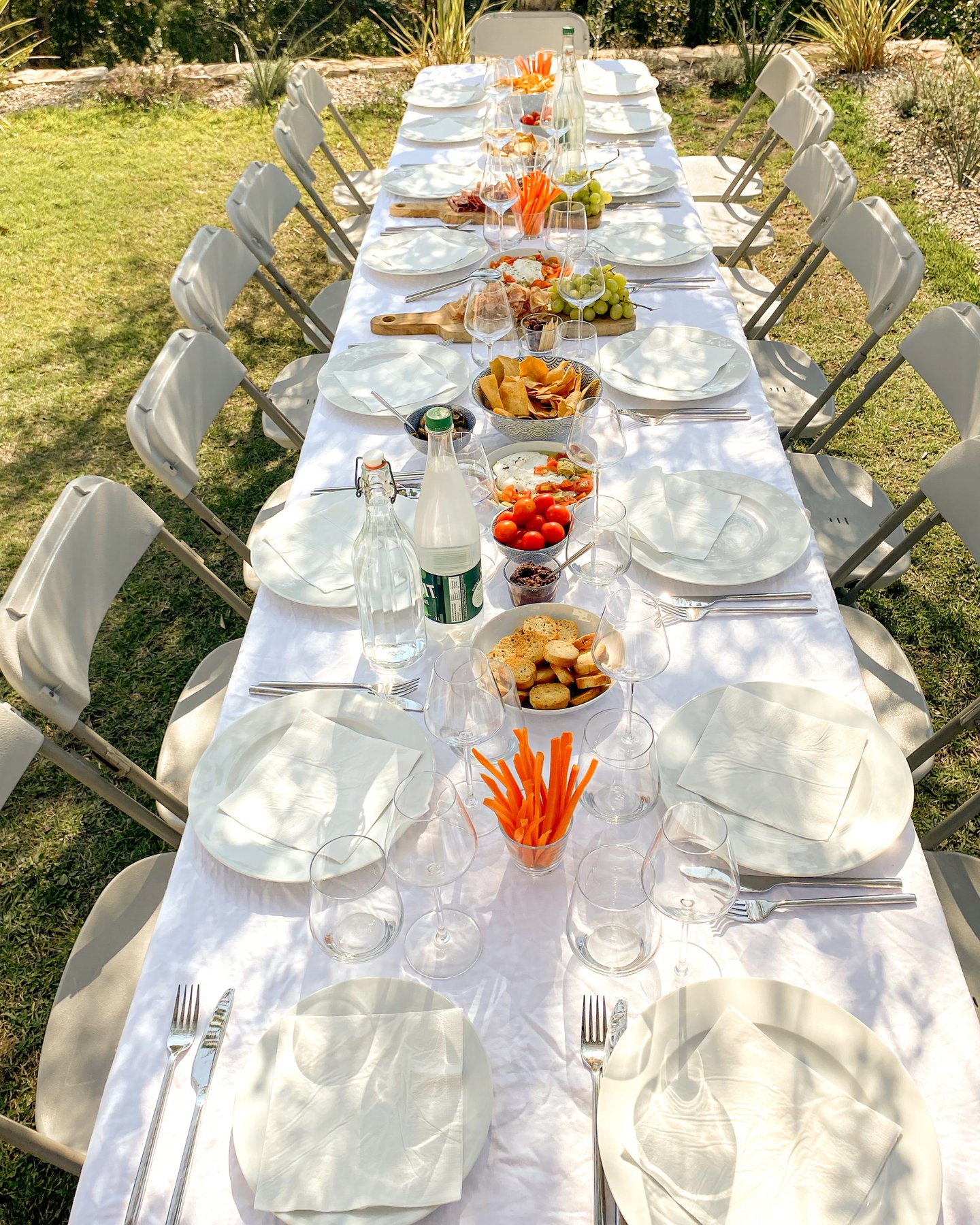 Long white table set under the olive trees