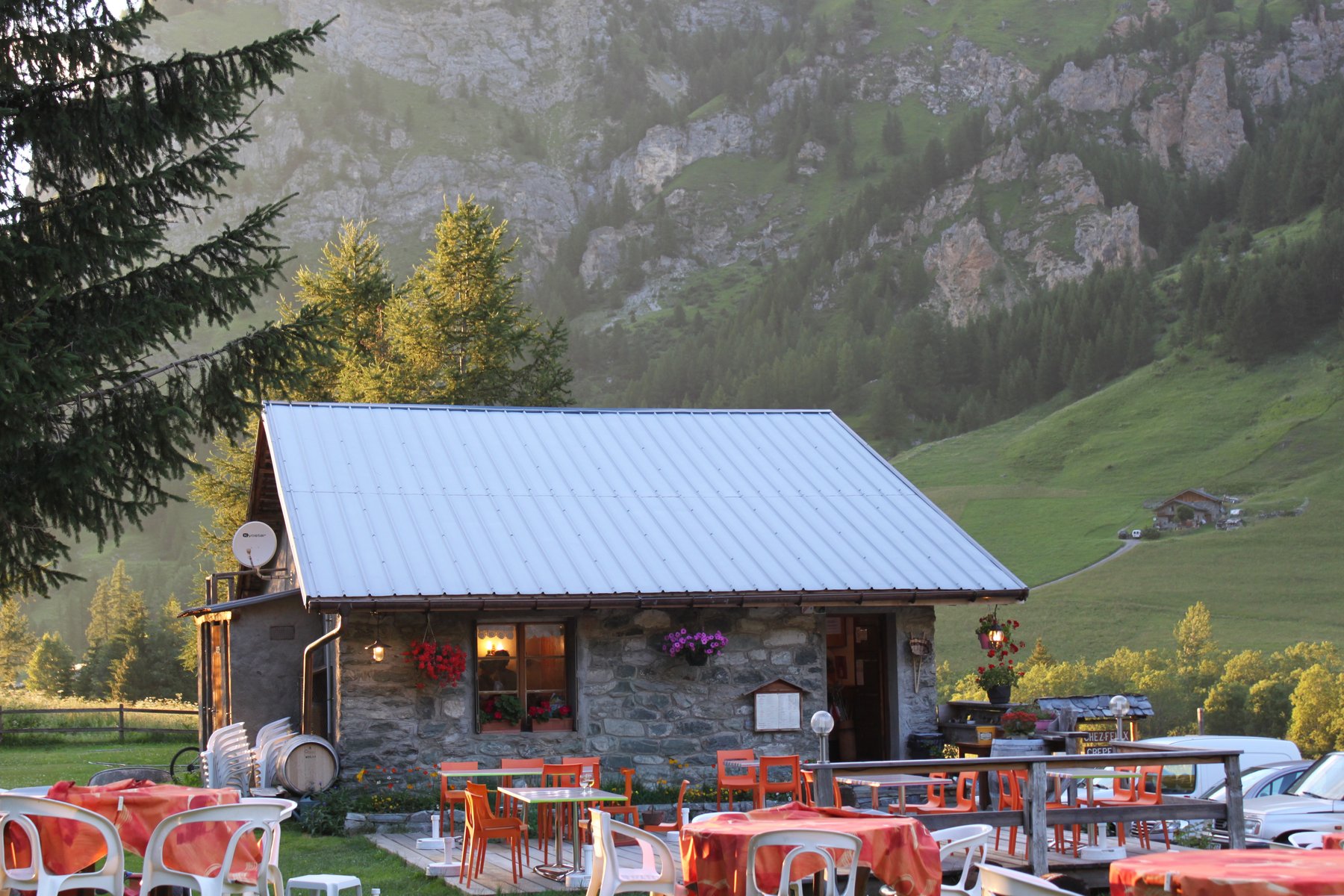 Stone mountain refuge with orange chairs on the terrace at golden hour